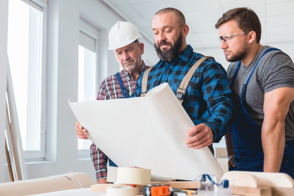 Group of builders looking at the house blueprint before renovation